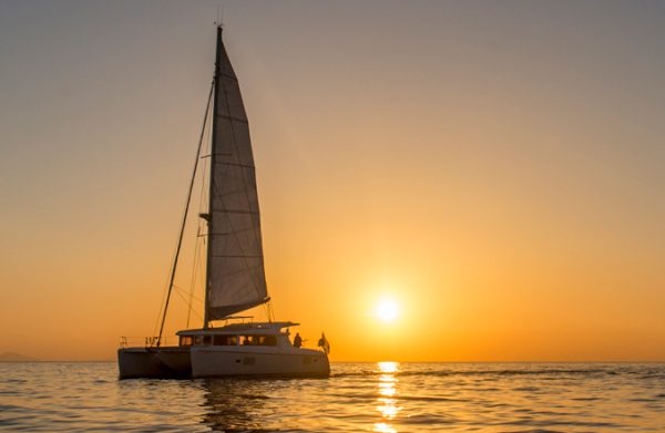 Catamaran sailing into the sunset over the Aegean off Santorini
