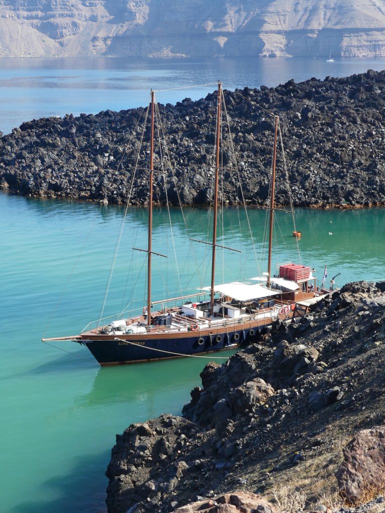 Excursion boat moored against the black lava shore of Nea Kameni, Santorini