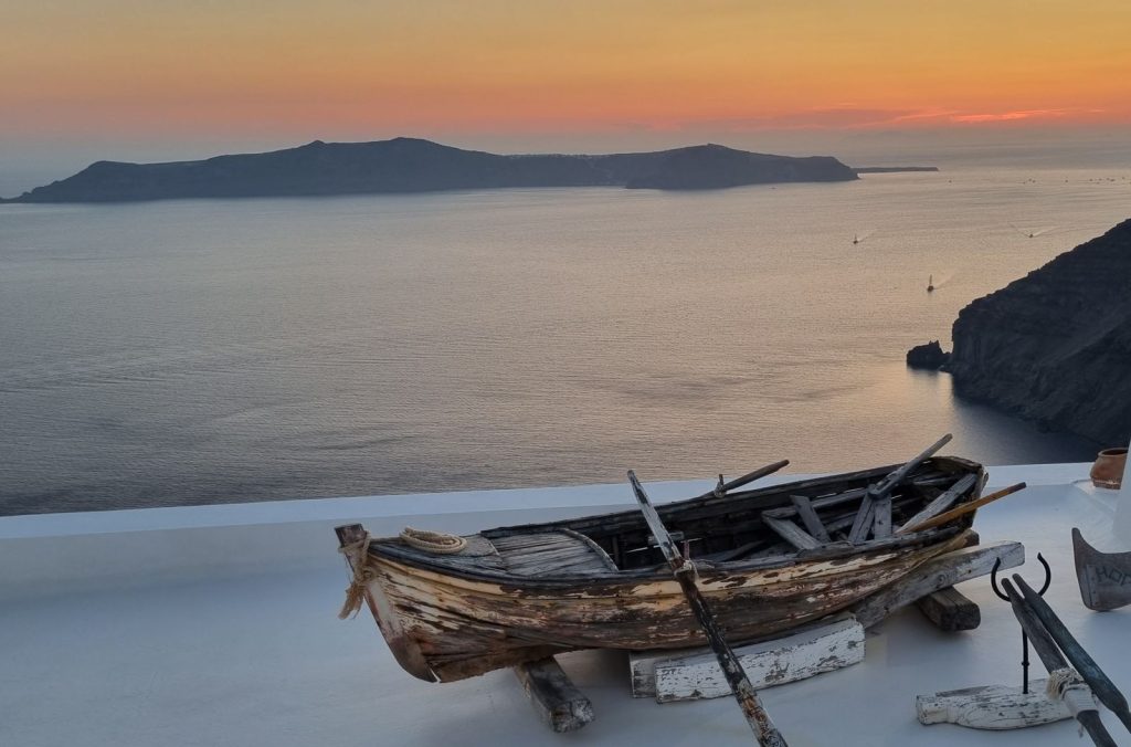 Sunset over the Santorini caldera, boats crossing the water below